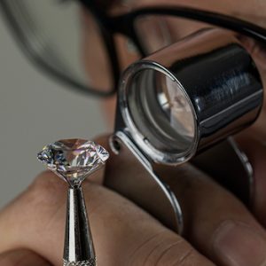 Jeweller Examines Polished Diamond Through a Magnifier.