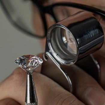 Jeweller Examines Polished Diamond Through a Magnifier.